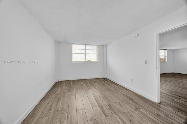 spare room featuring a textured ceiling and light hardwood / wood-style flooring