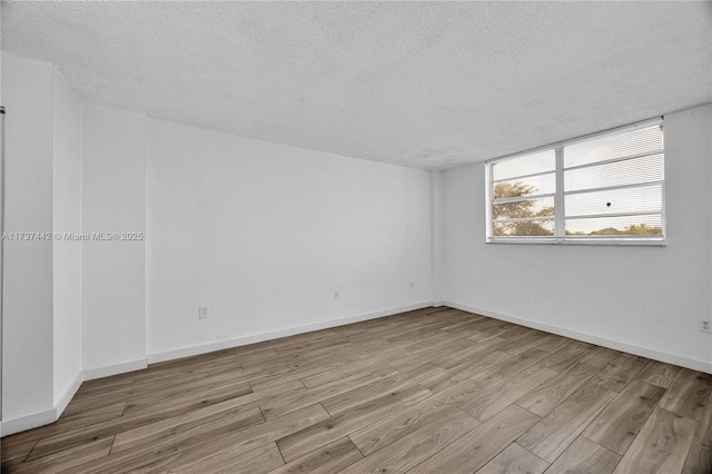 unfurnished room with a textured ceiling and light wood-type flooring