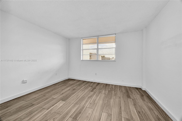 empty room with light hardwood / wood-style floors and a textured ceiling