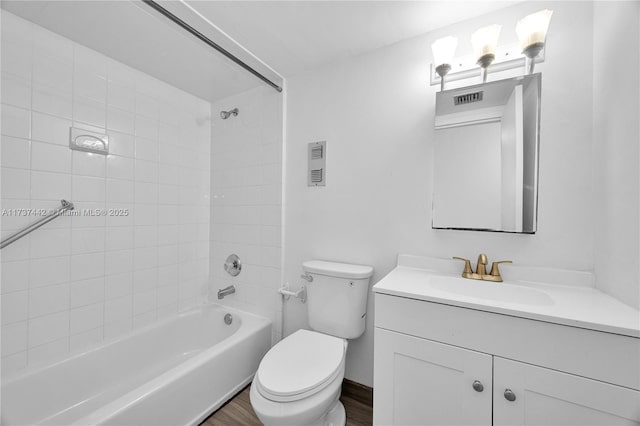 full bathroom with vanity, tiled shower / bath, hardwood / wood-style flooring, and toilet