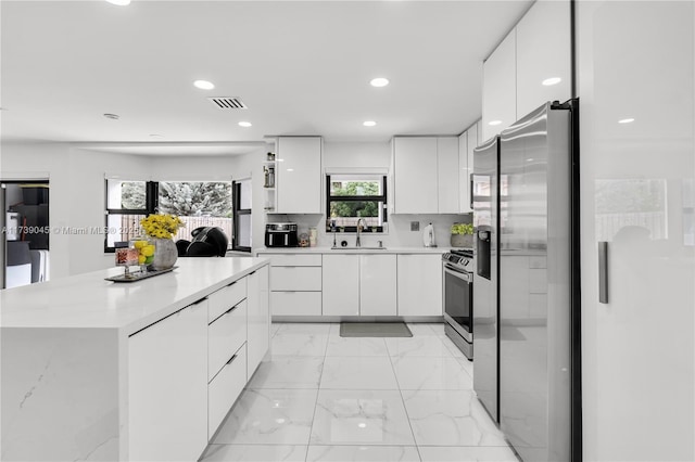 kitchen with a kitchen island, sink, white cabinets, backsplash, and stainless steel appliances