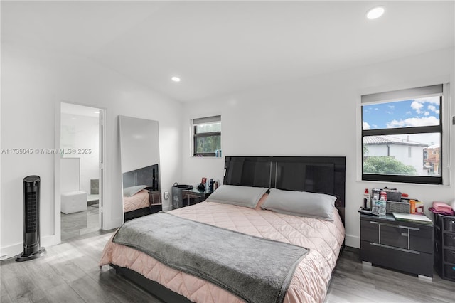 bedroom with lofted ceiling, connected bathroom, and hardwood / wood-style floors