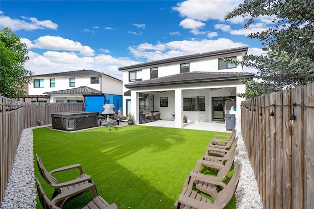 rear view of house featuring ceiling fan, a yard, a hot tub, and a patio