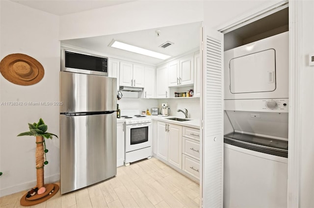 kitchen featuring white cabinetry, sink, stacked washer / dryer, and appliances with stainless steel finishes