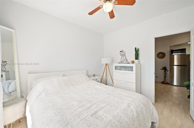 bedroom with ceiling fan, light wood-type flooring, and stainless steel refrigerator