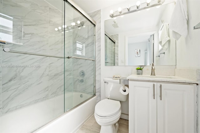 full bathroom featuring bath / shower combo with glass door, vanity, and toilet