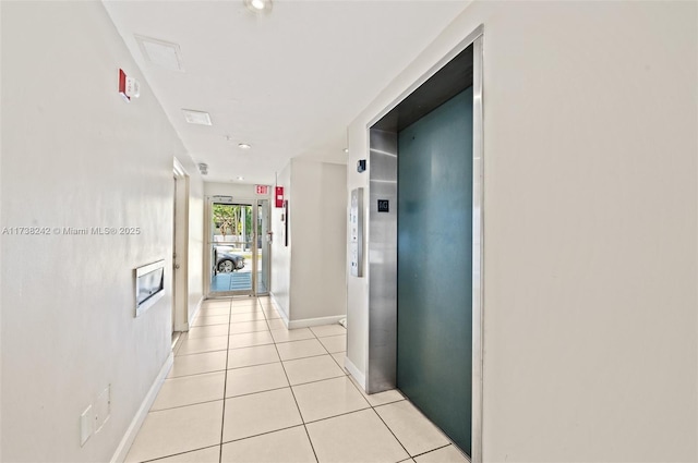 hall featuring elevator and light tile patterned floors