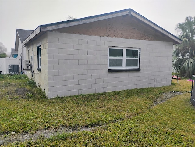 view of side of home with central AC unit and a lawn