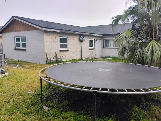 rear view of house featuring a yard and a trampoline