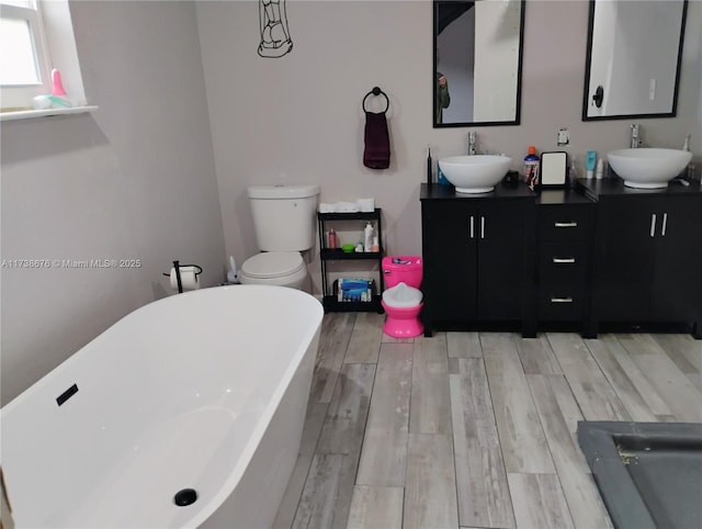 bathroom featuring hardwood / wood-style flooring, vanity, a tub, and toilet