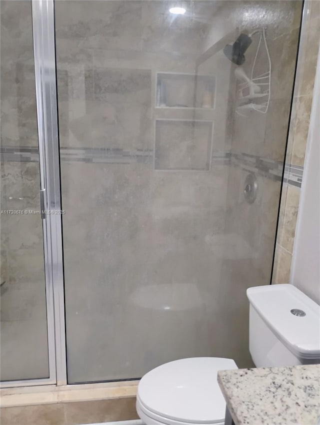 bathroom with toilet, an enclosed shower, and tile walls