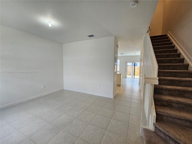 unfurnished room with light tile patterned flooring and a textured ceiling