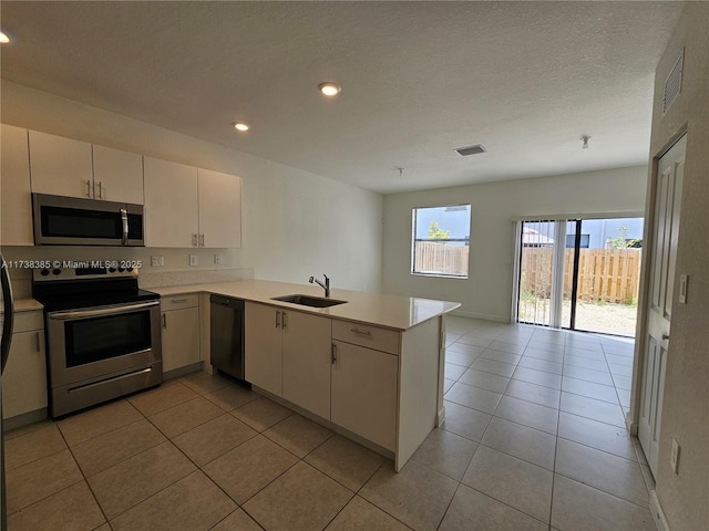 kitchen featuring light tile patterned flooring, sink, a textured ceiling, kitchen peninsula, and stainless steel appliances