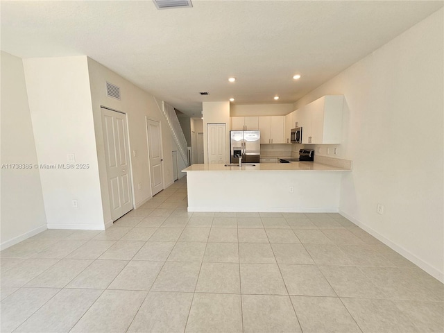 kitchen featuring light tile patterned floors, sink, white cabinetry, stainless steel appliances, and kitchen peninsula