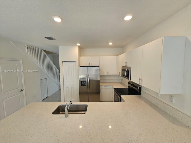 kitchen with sink, white cabinetry, a textured ceiling, appliances with stainless steel finishes, and kitchen peninsula