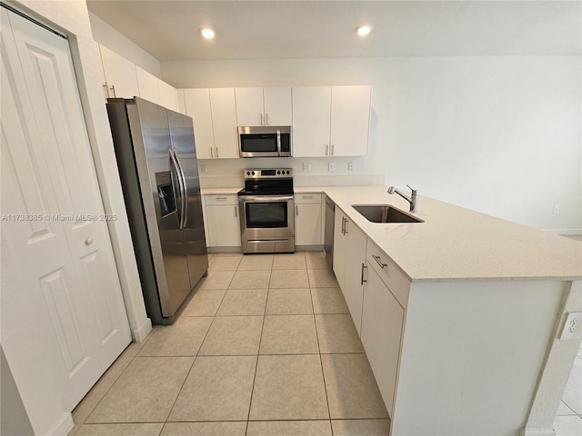 kitchen with sink, light tile patterned floors, appliances with stainless steel finishes, kitchen peninsula, and white cabinets