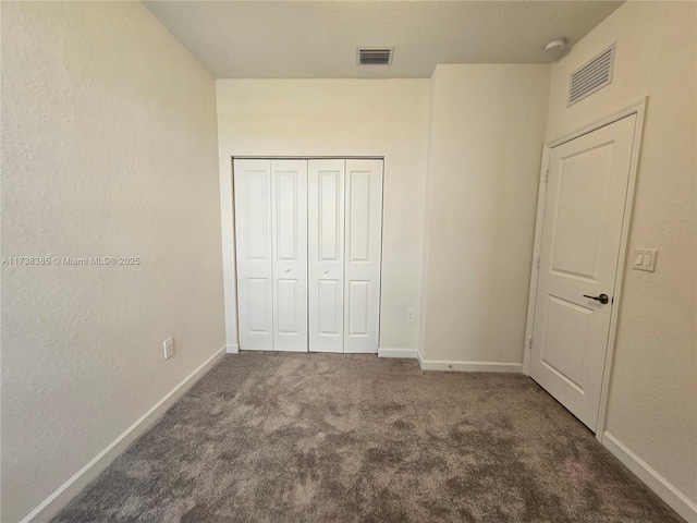 unfurnished bedroom featuring a closet and dark colored carpet