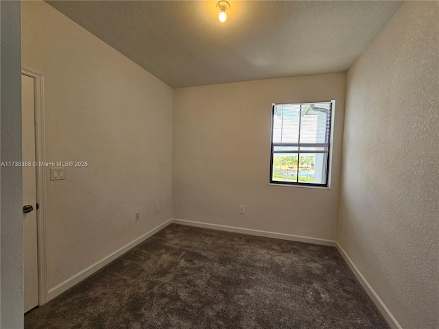 empty room featuring dark carpet and a textured ceiling