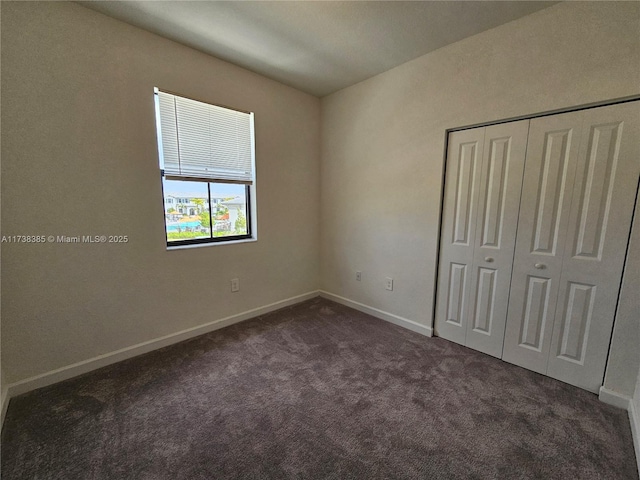 unfurnished bedroom featuring a closet and dark colored carpet