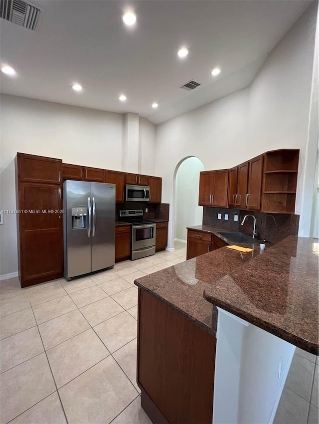 kitchen featuring sink, backsplash, kitchen peninsula, and appliances with stainless steel finishes