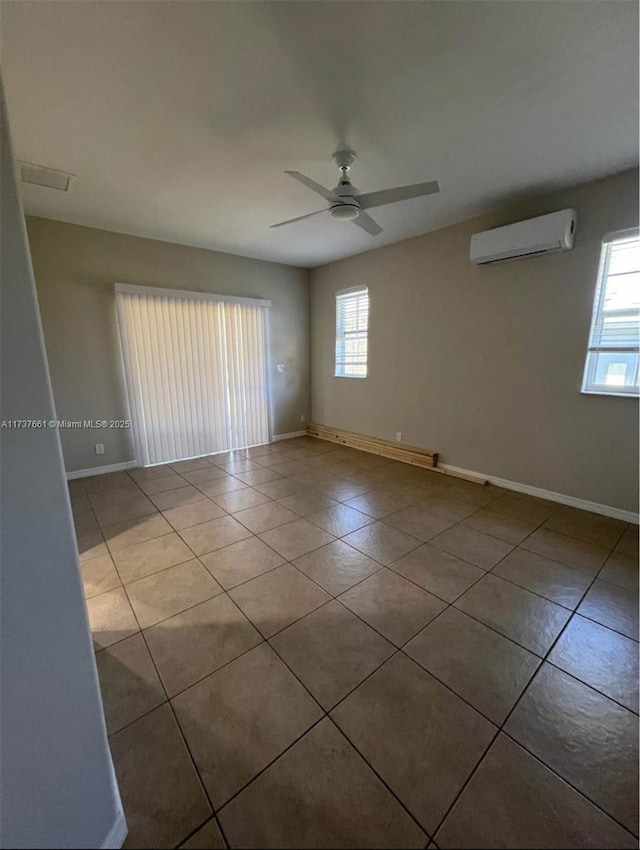 empty room featuring plenty of natural light, a wall unit AC, ceiling fan, and light tile patterned flooring