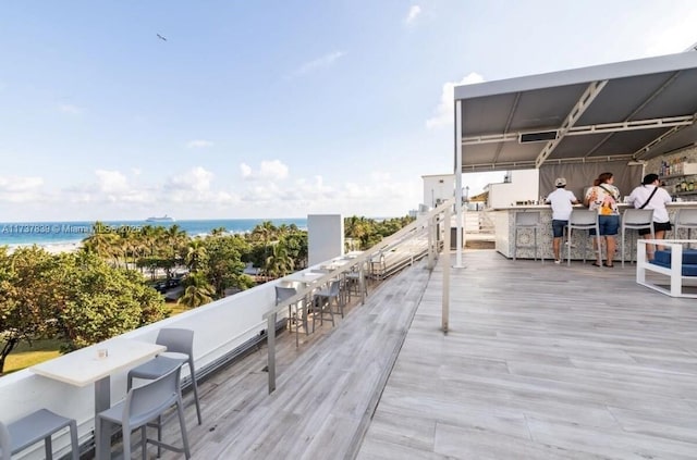 wooden terrace featuring a bar and a water view