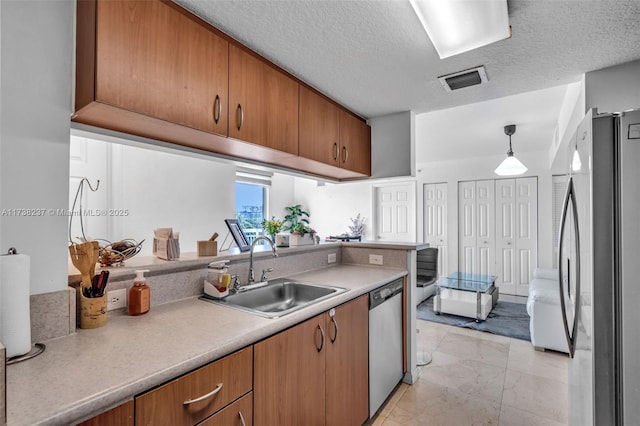 kitchen with pendant lighting, sink, a textured ceiling, and appliances with stainless steel finishes