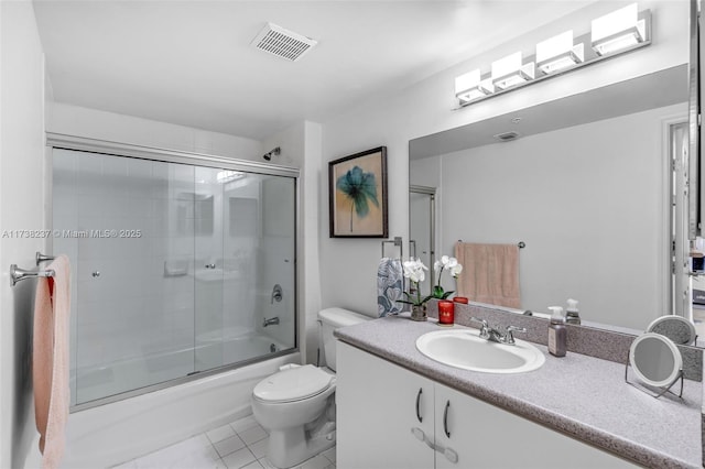 full bathroom with vanity, bath / shower combo with glass door, tile patterned floors, and toilet