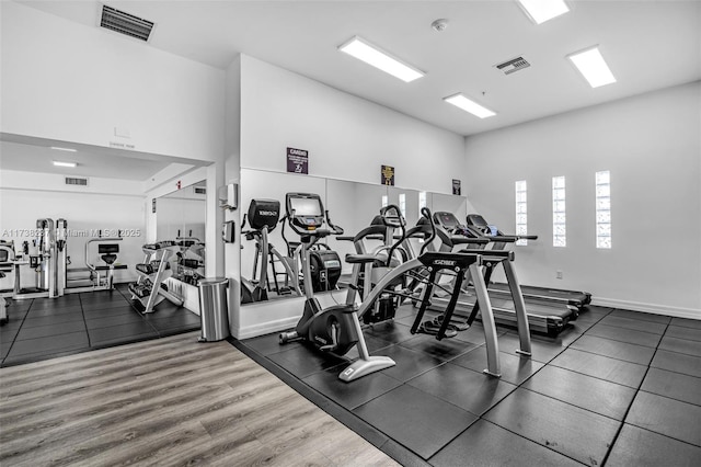 exercise room with dark wood-type flooring and a high ceiling