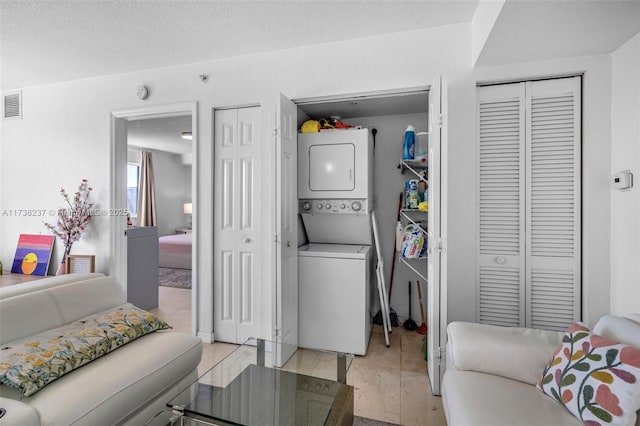 clothes washing area featuring stacked washer and clothes dryer