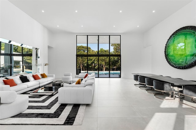 living room with light tile patterned floors, a wall of windows, a high ceiling, and plenty of natural light