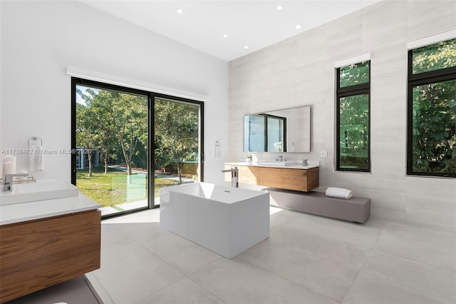 bathroom with tile patterned flooring, vanity, a bathing tub, and tile walls