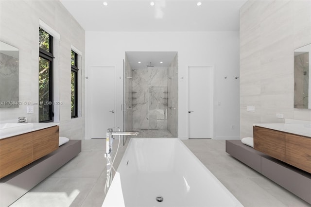 bathroom with independent shower and bath, vanity, tile patterned flooring, and tile walls