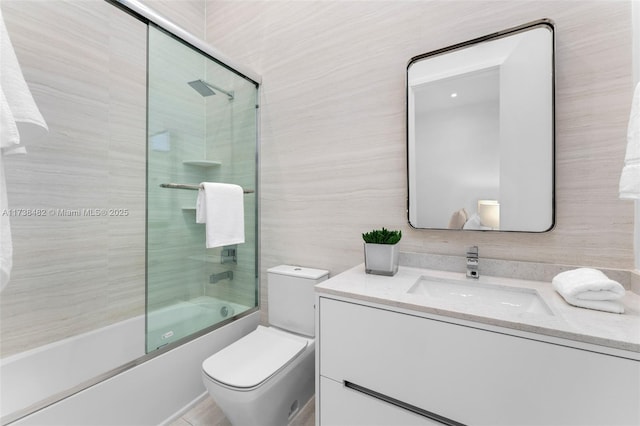 full bathroom with bath / shower combo with glass door, vanity, and toilet