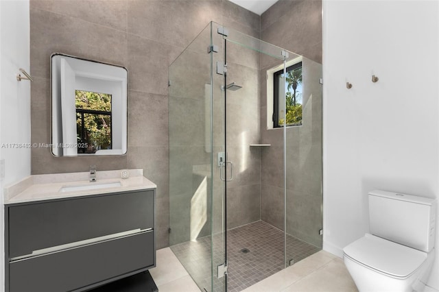 bathroom featuring a shower with door, vanity, tile patterned floors, and toilet