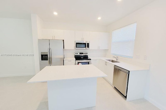 kitchen with a kitchen island, appliances with stainless steel finishes, sink, and white cabinets