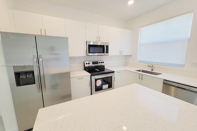 kitchen with light stone countertops, white cabinetry, appliances with stainless steel finishes, and sink