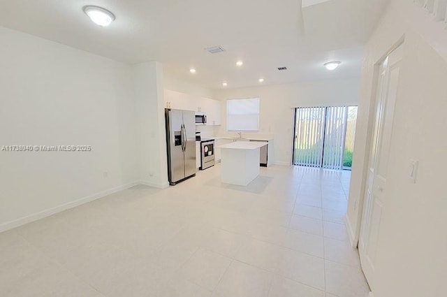 kitchen with sink, stainless steel appliances, a center island, white cabinets, and light tile patterned flooring