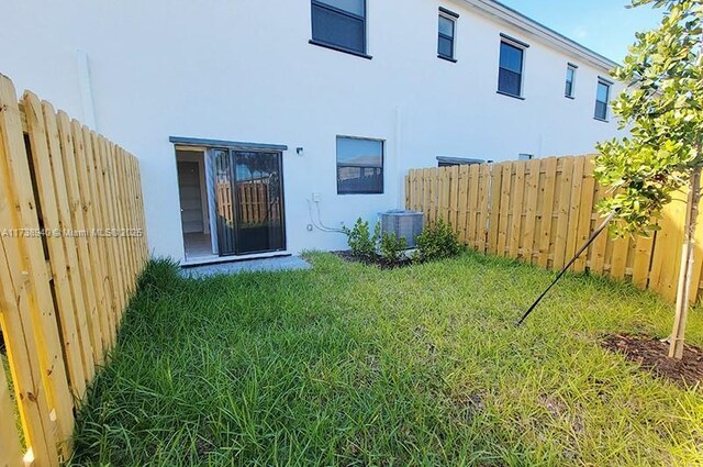 rear view of property with central AC and a lawn