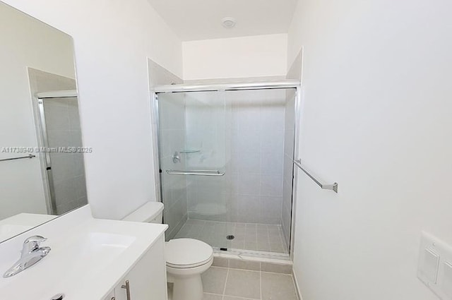 bathroom with vanity, toilet, a shower with shower door, and tile patterned flooring