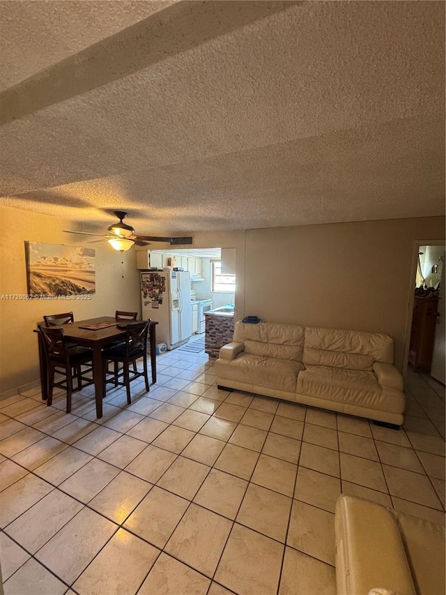 living room with ceiling fan, light tile patterned floors, and a textured ceiling