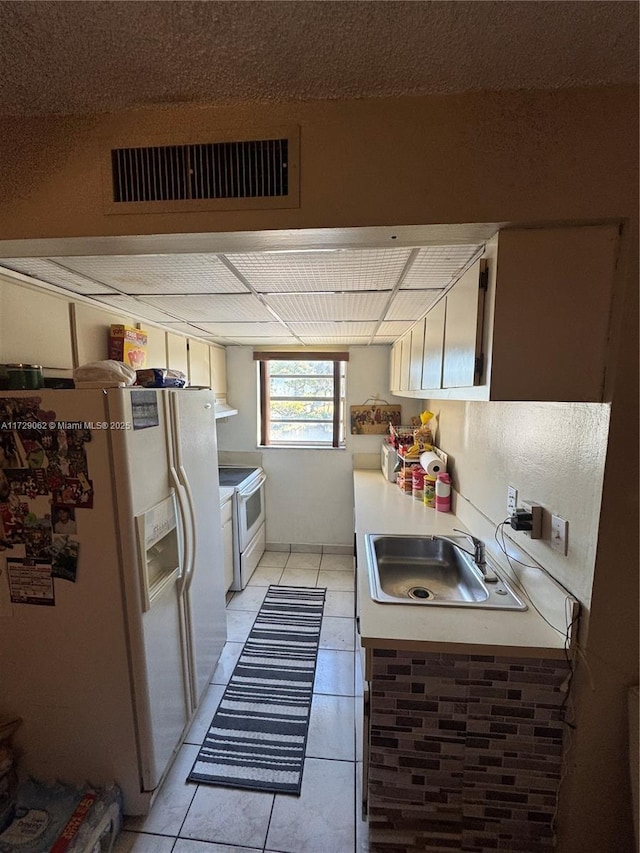 kitchen featuring white appliances, sink, and light tile patterned floors