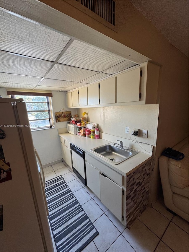 kitchen featuring sink, white appliances, light tile patterned floors, and white cabinets