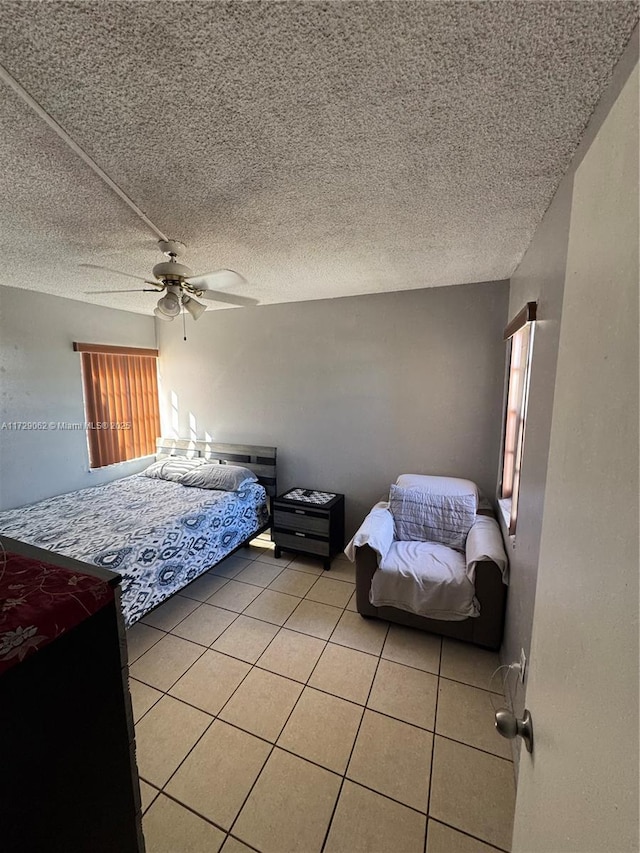 bedroom with ceiling fan, a textured ceiling, and light tile patterned floors