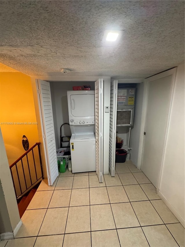 clothes washing area featuring light tile patterned flooring, stacked washing maching and dryer, and a textured ceiling