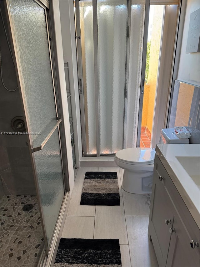 bathroom featuring tile patterned flooring, vanity, an enclosed shower, and toilet