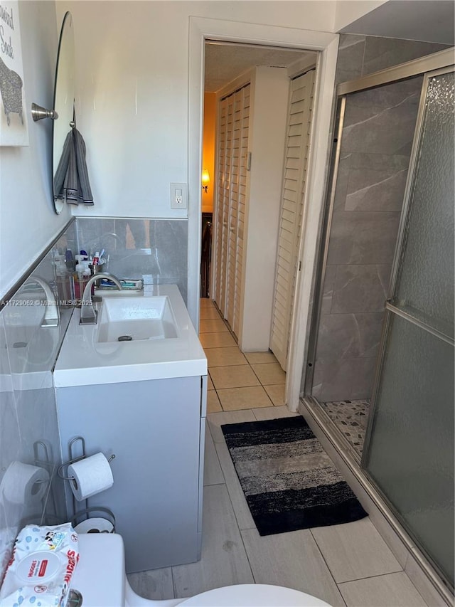 bathroom with toilet, vanity, a shower with door, and tile patterned flooring