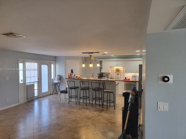 kitchen featuring tasteful backsplash, dishwasher, a breakfast bar area, white cabinets, and hanging light fixtures