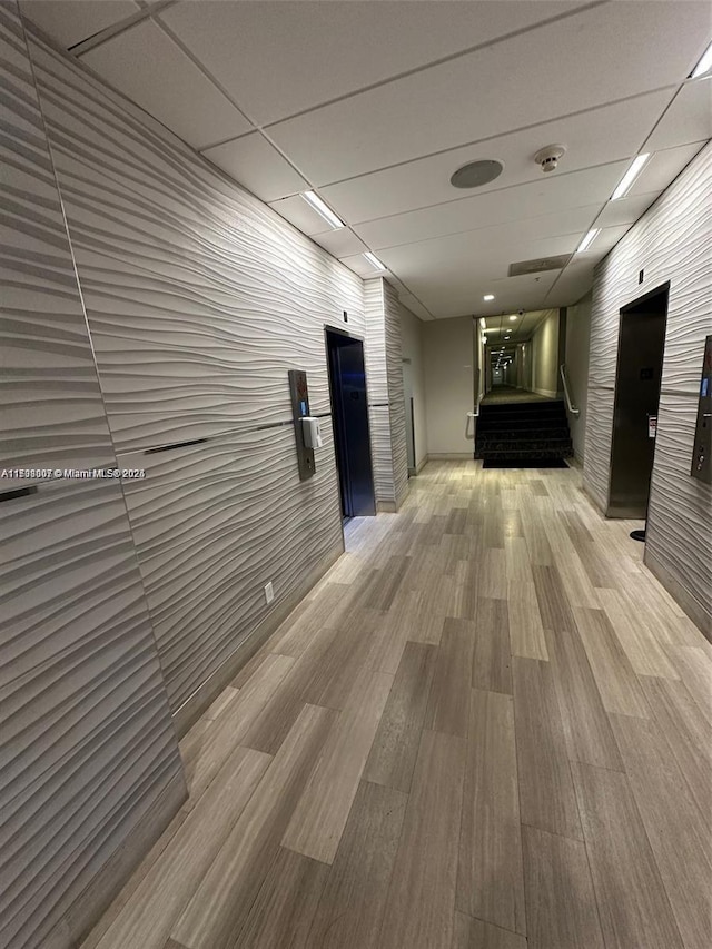 corridor featuring a drop ceiling and hardwood / wood-style floors