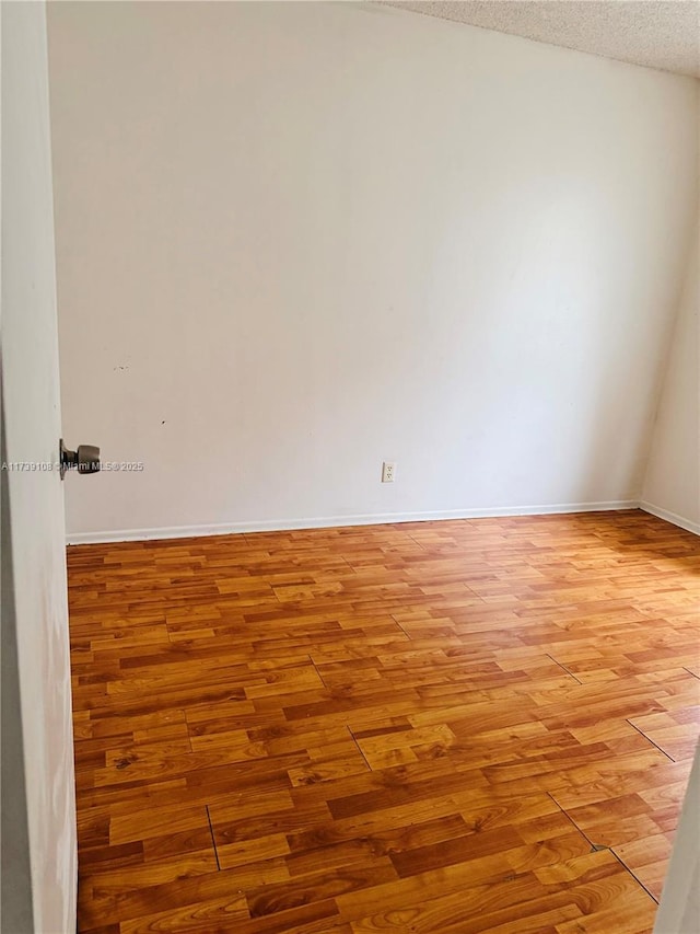 empty room with a textured ceiling and light wood-type flooring